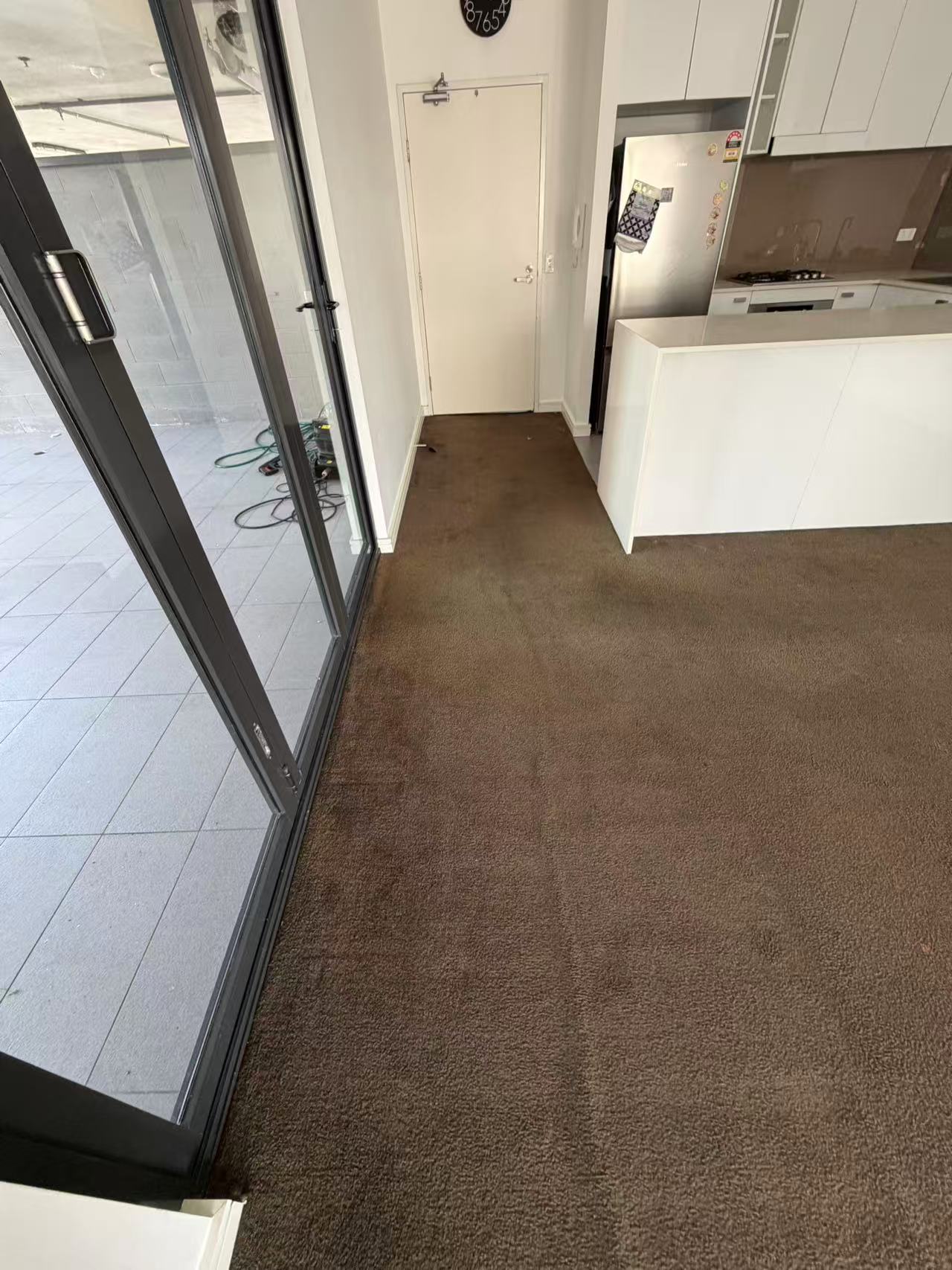 Brown carpet beside a kitchen and balcony doors