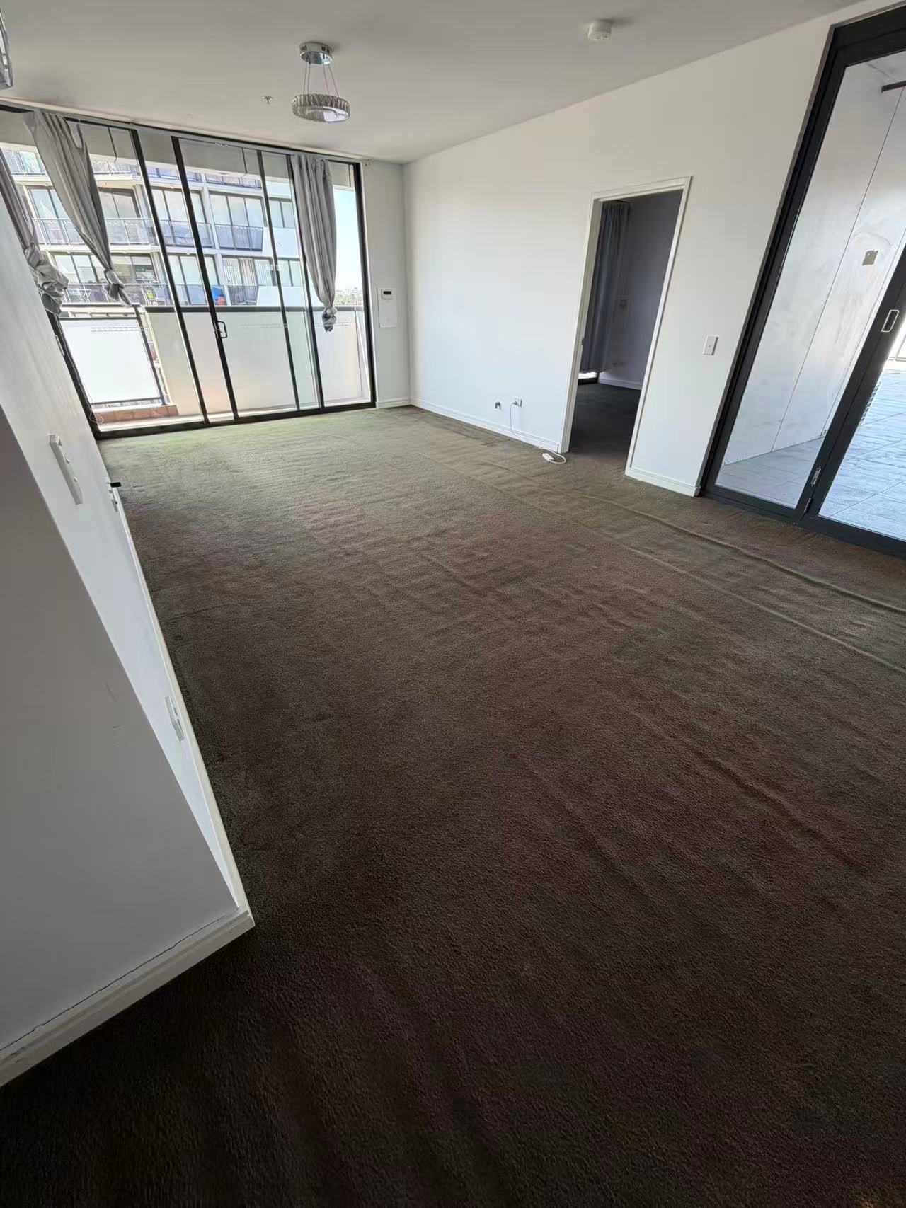 Brown carpet in a living room beside balcony doors