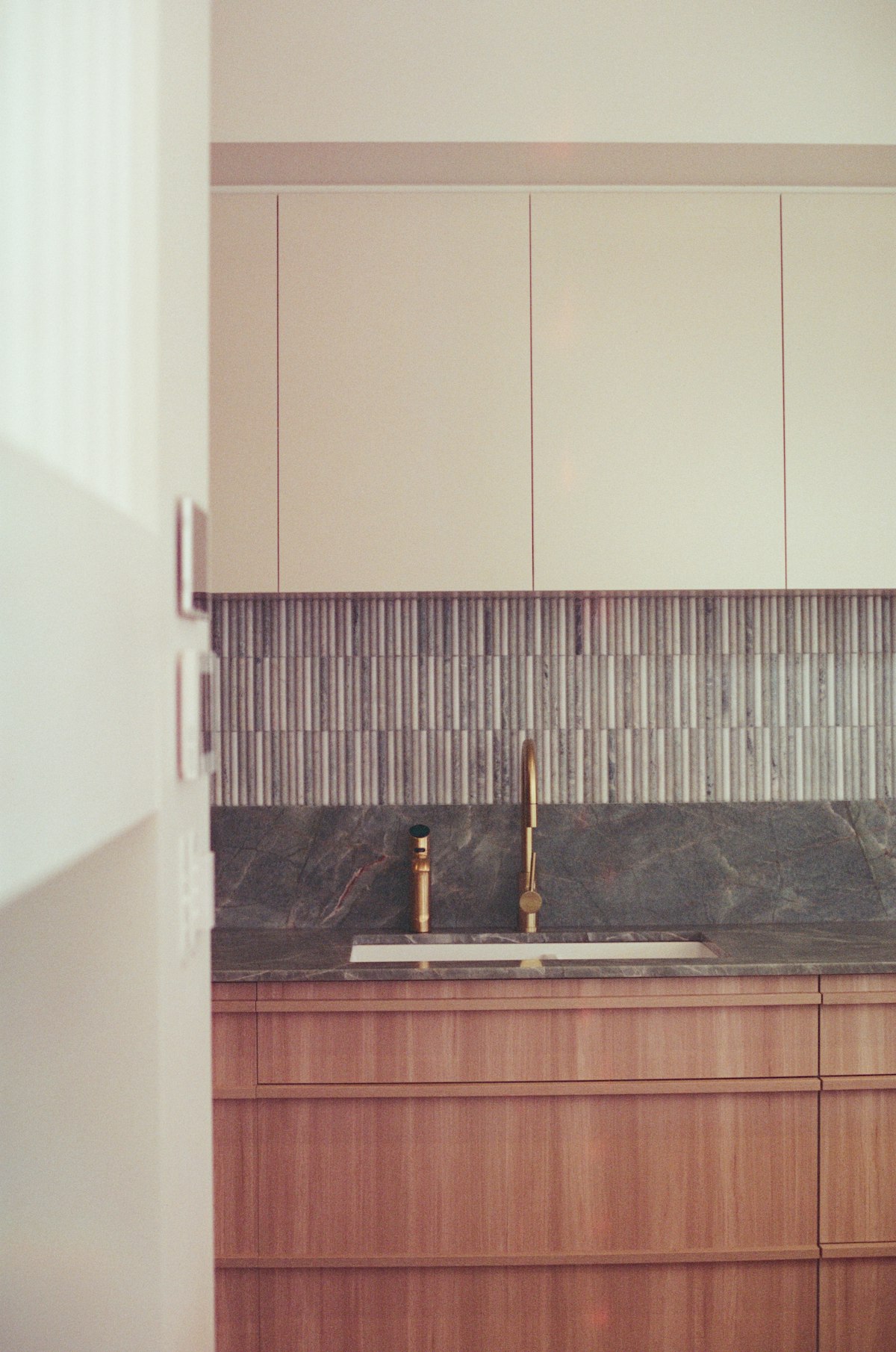 Timber kitchen cabinets, vertical splashback tiles and sink
