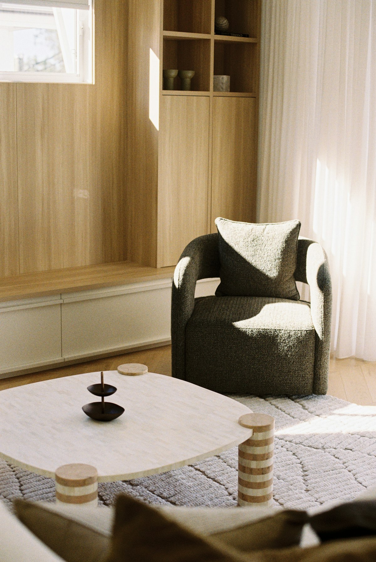 Living room with built-in timber storage, chair and natural light