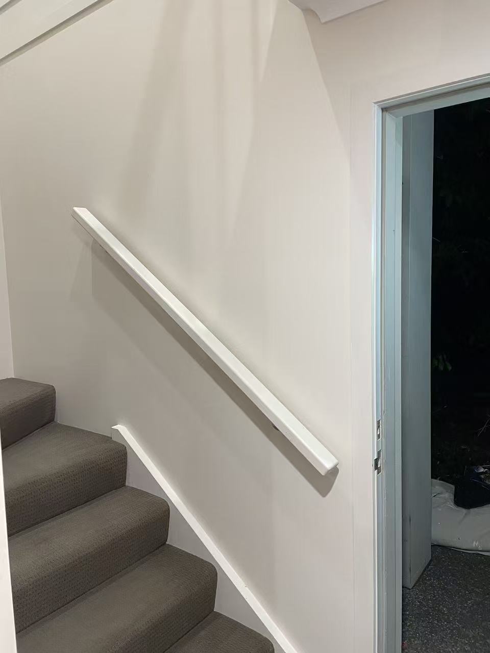 Freshly painted light wall and handrail beside an interior stair