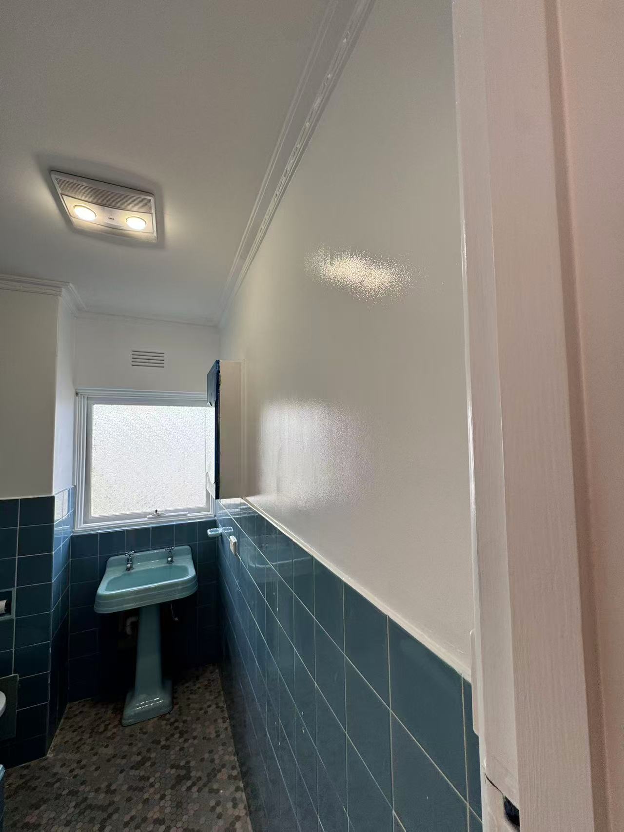 Bathroom wall meeting existing blue tiles beside a vanity