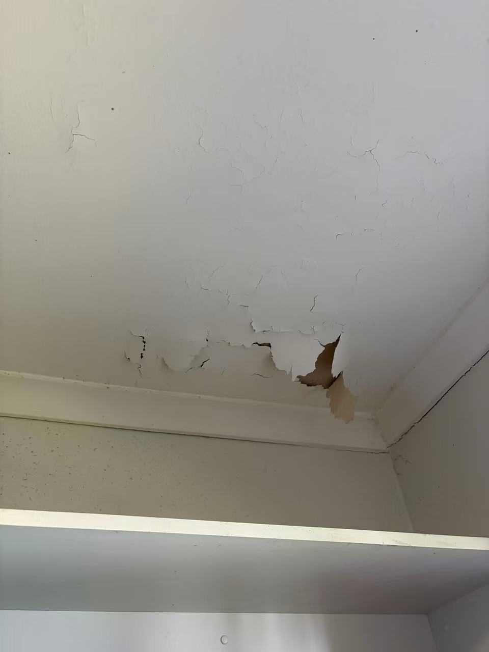 Peeling ceiling surface and cracks in a room
